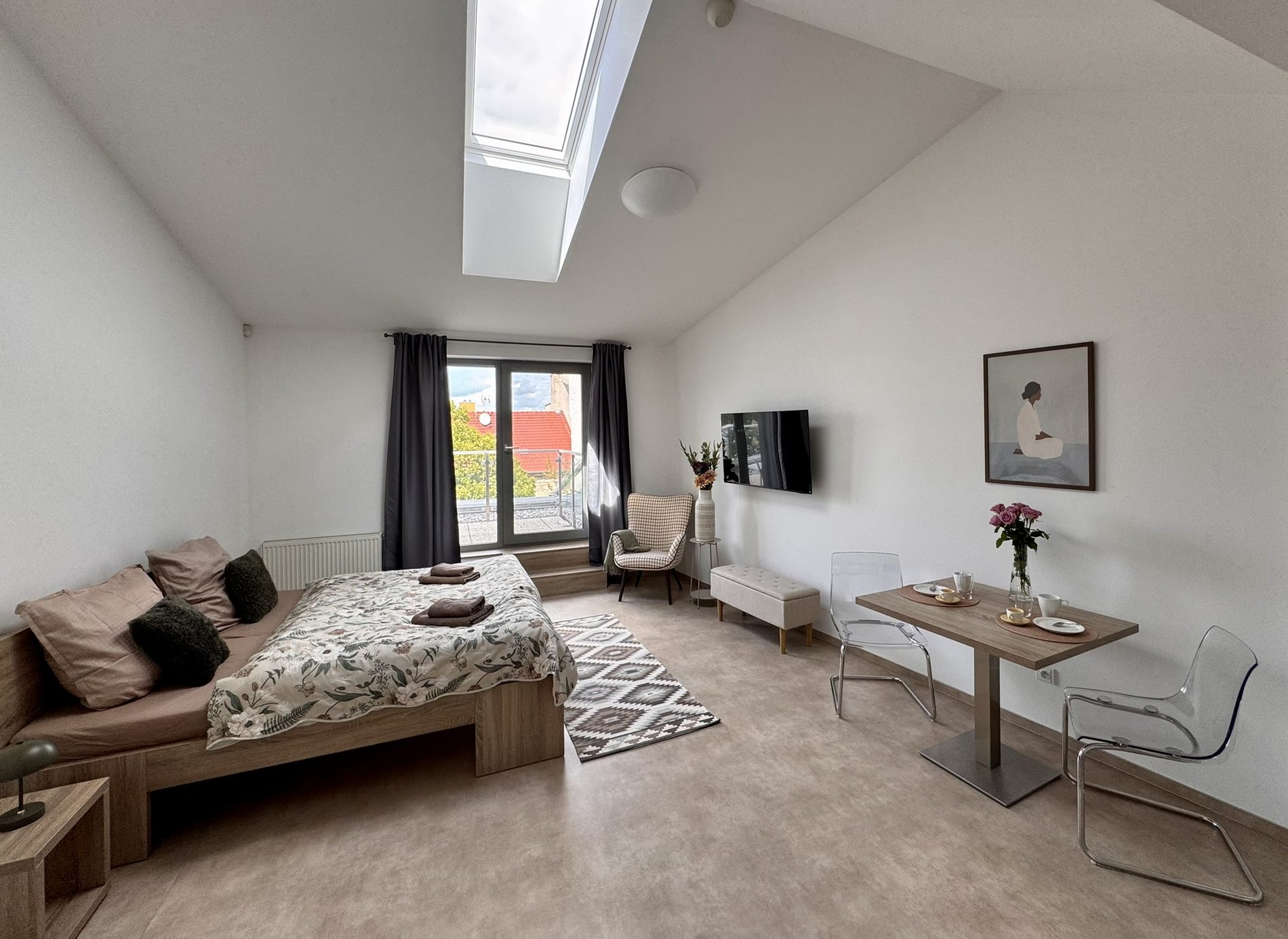 Podkrovní apartmán GIA Clinic — postel, jídelní stůl a balkon